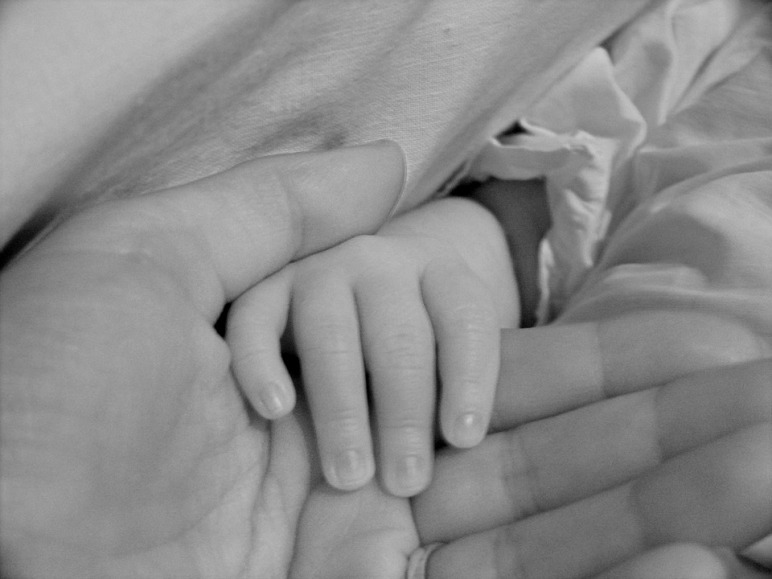 A mother holding the fingers of a child.